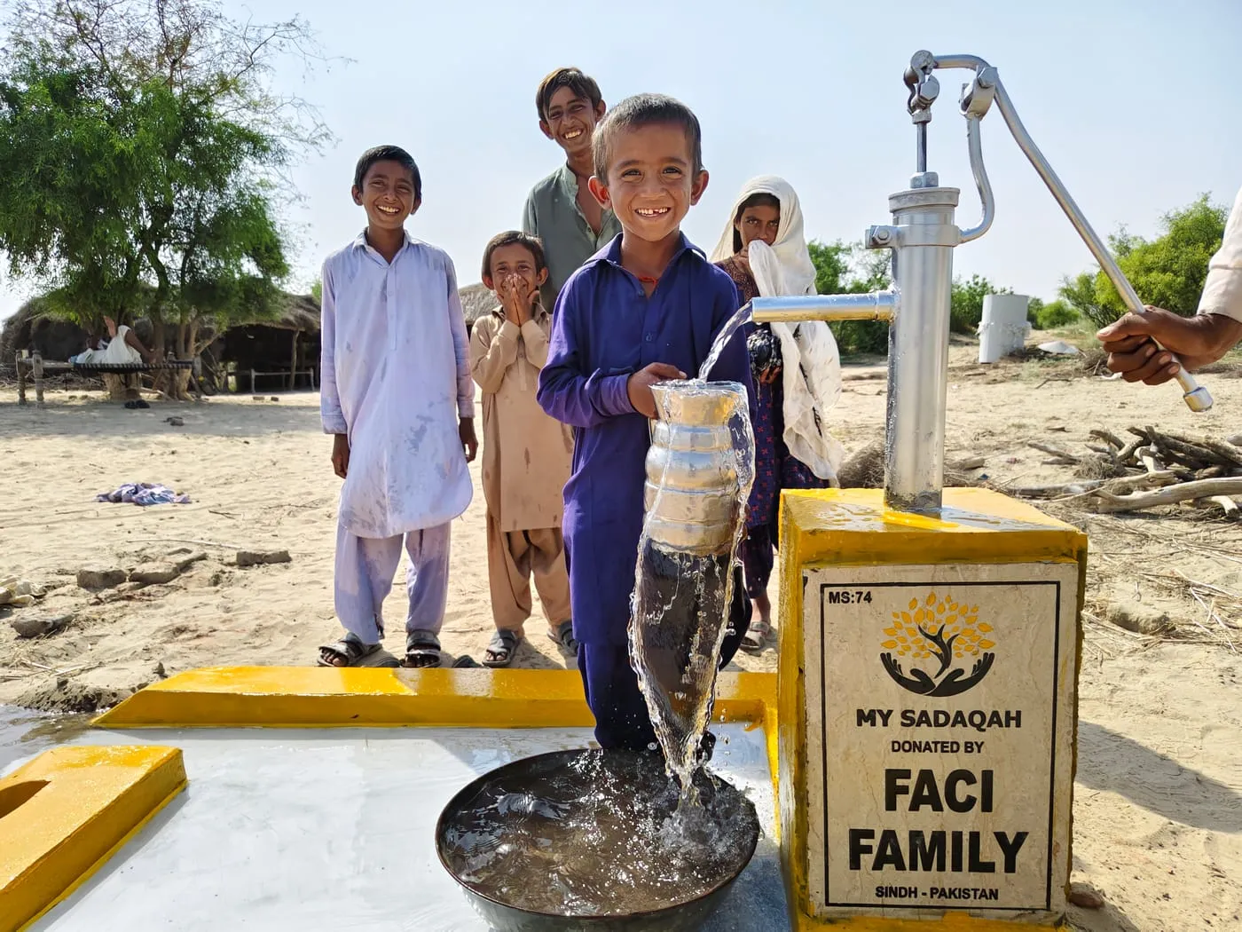 Children gathered around a My Sadaqah hand pump